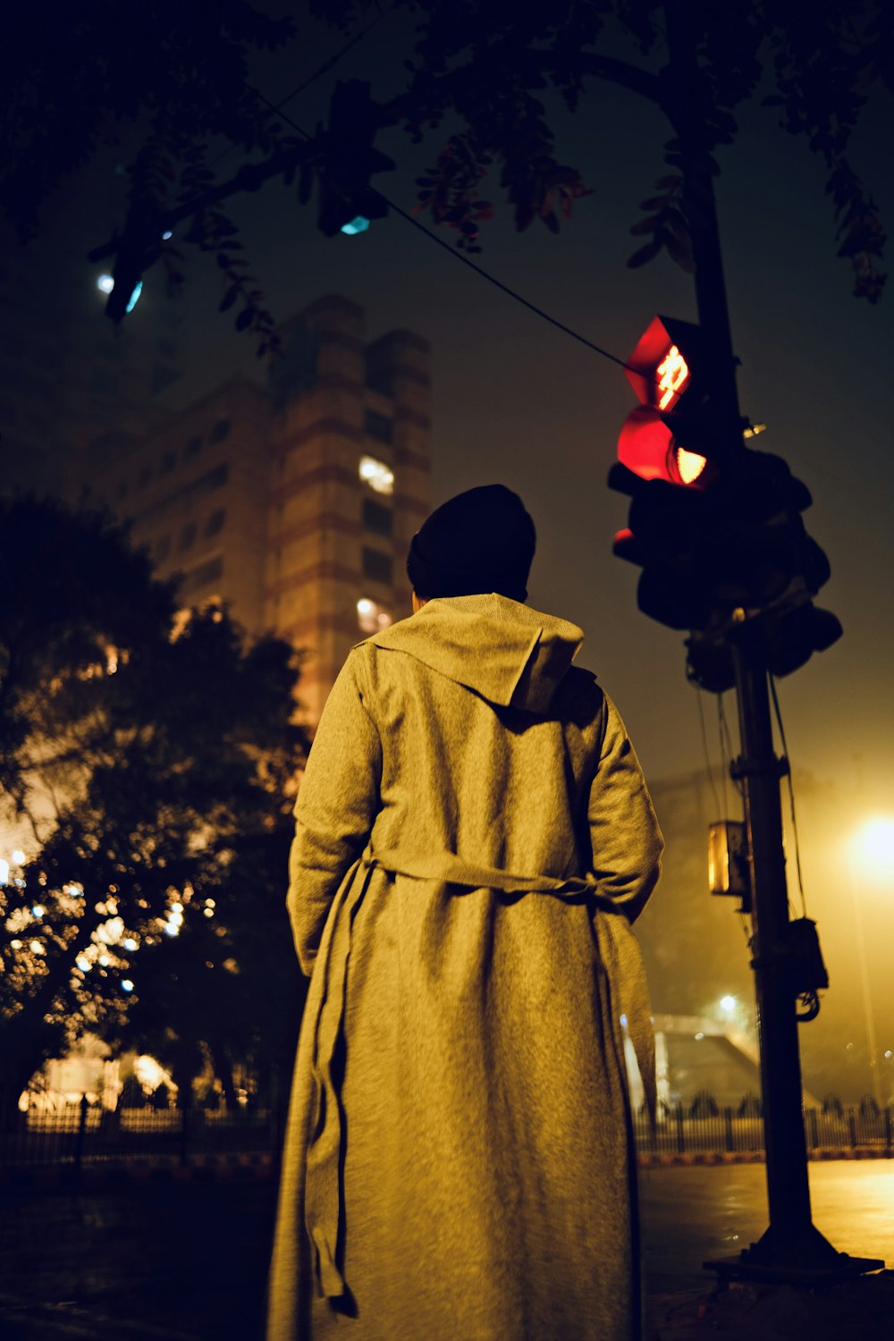 a man standing next to a traffic light at night