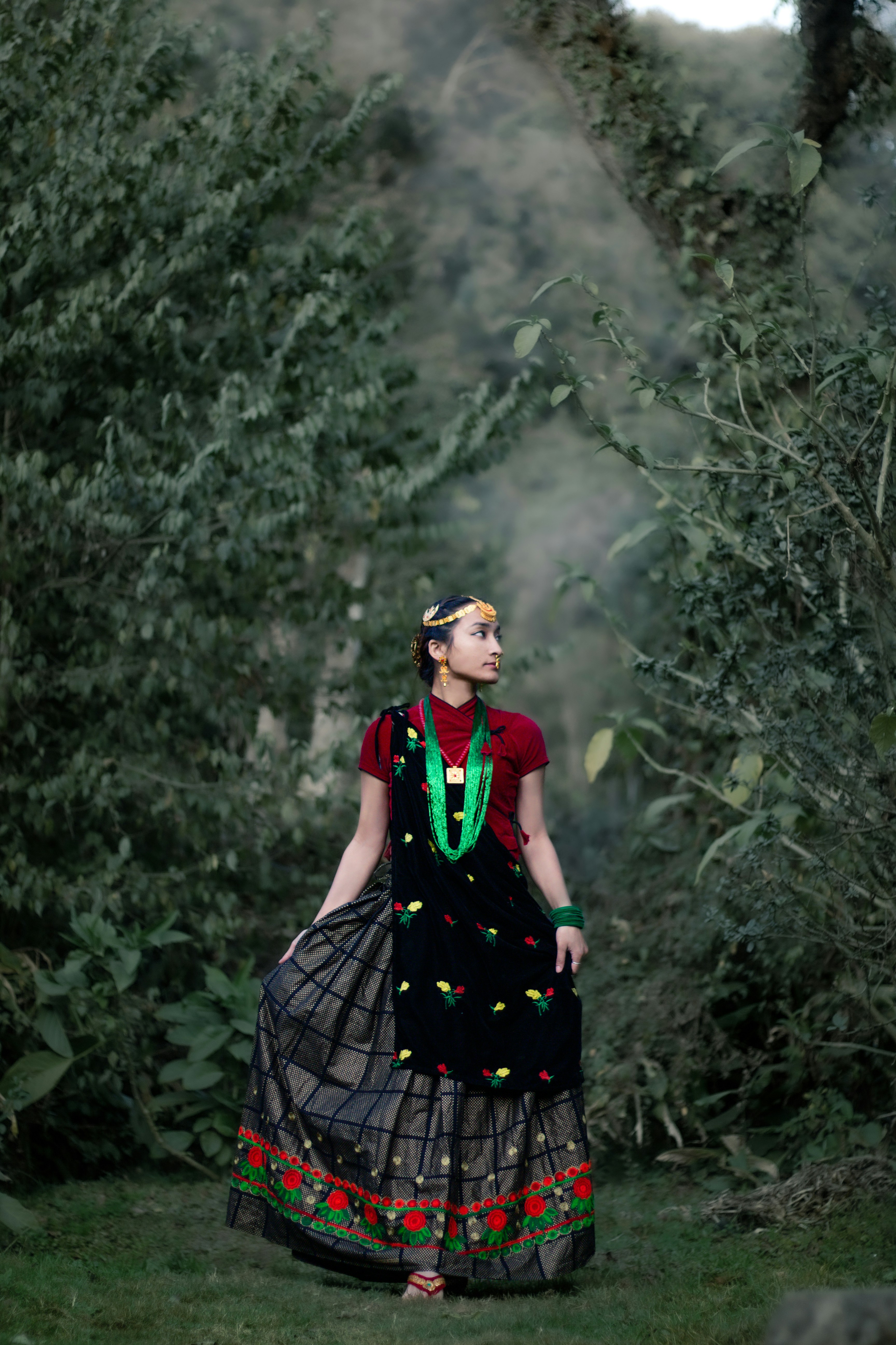 a woman in a dress walking through a forest