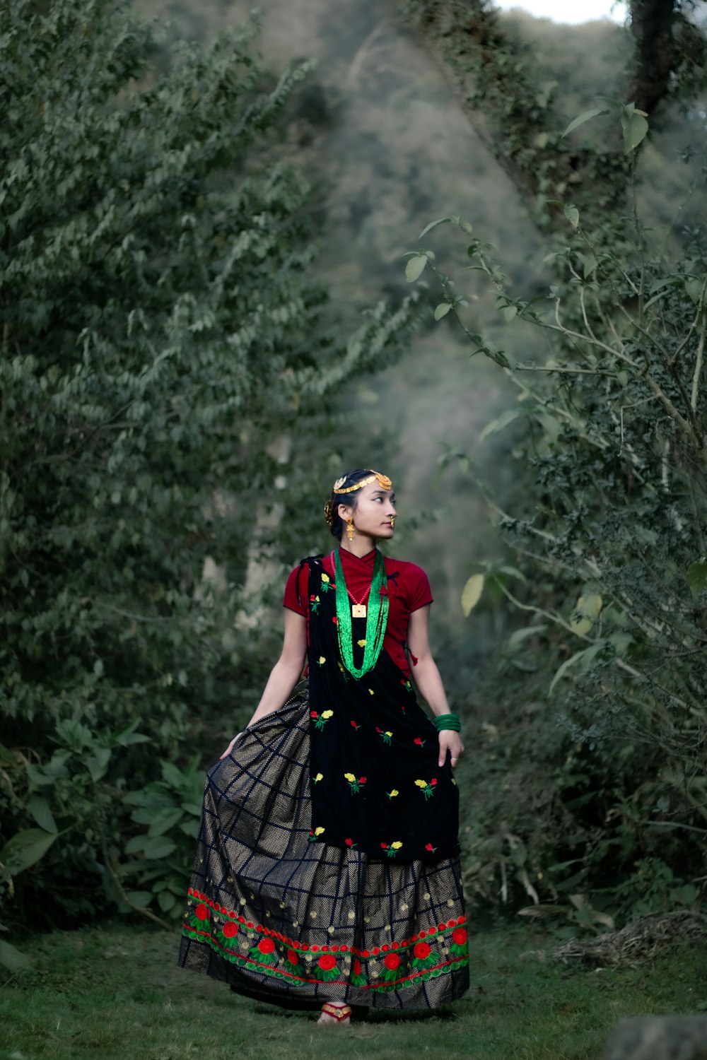 a woman in a dress walking through a forest