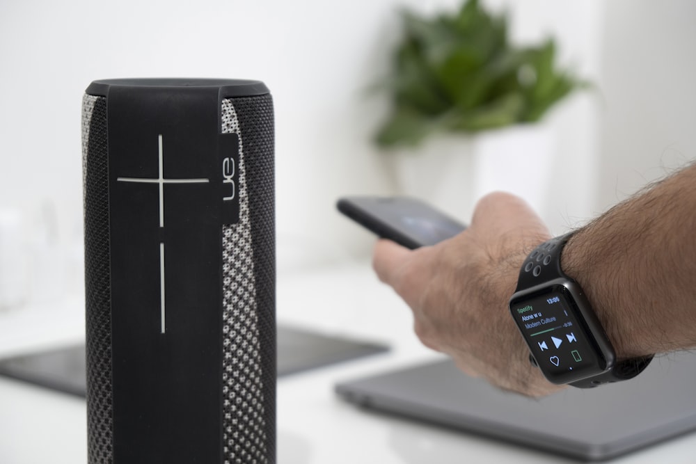 a person holding a cell phone next to a speaker