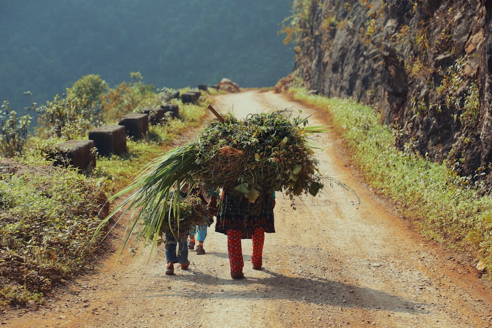 a woman and two children walking down a dirt road