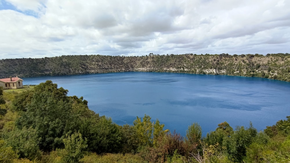 un grand lac bleu entouré d’arbres par temps nuageux