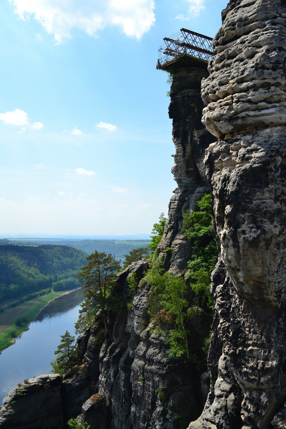 a man standing on top of a cliff next to a river
