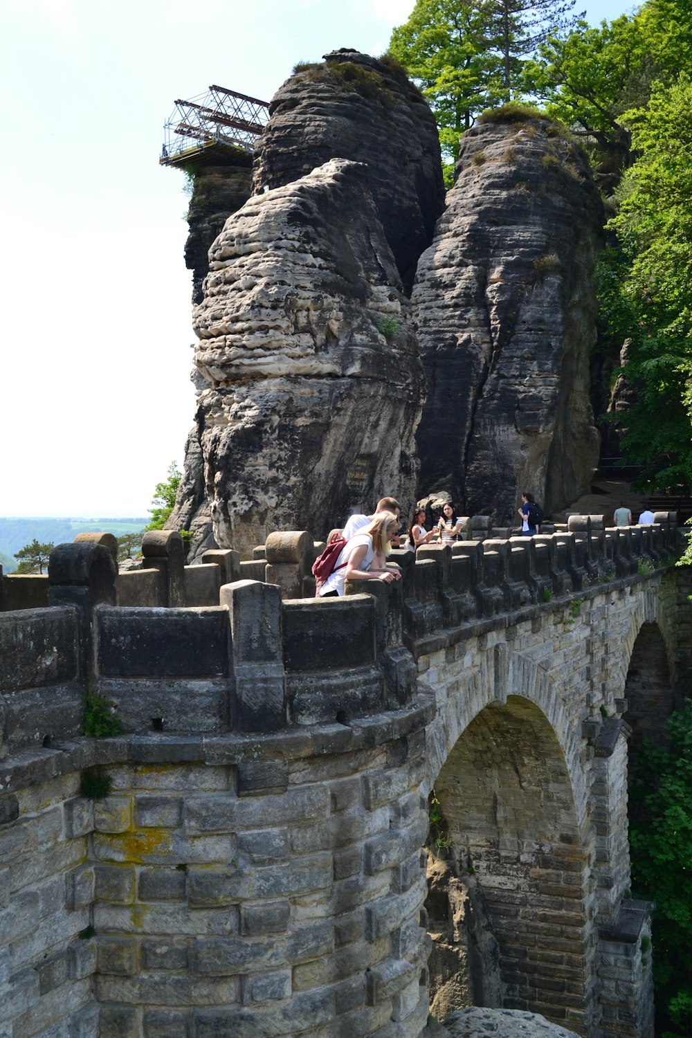 a group of people standing on top of a stone bridge