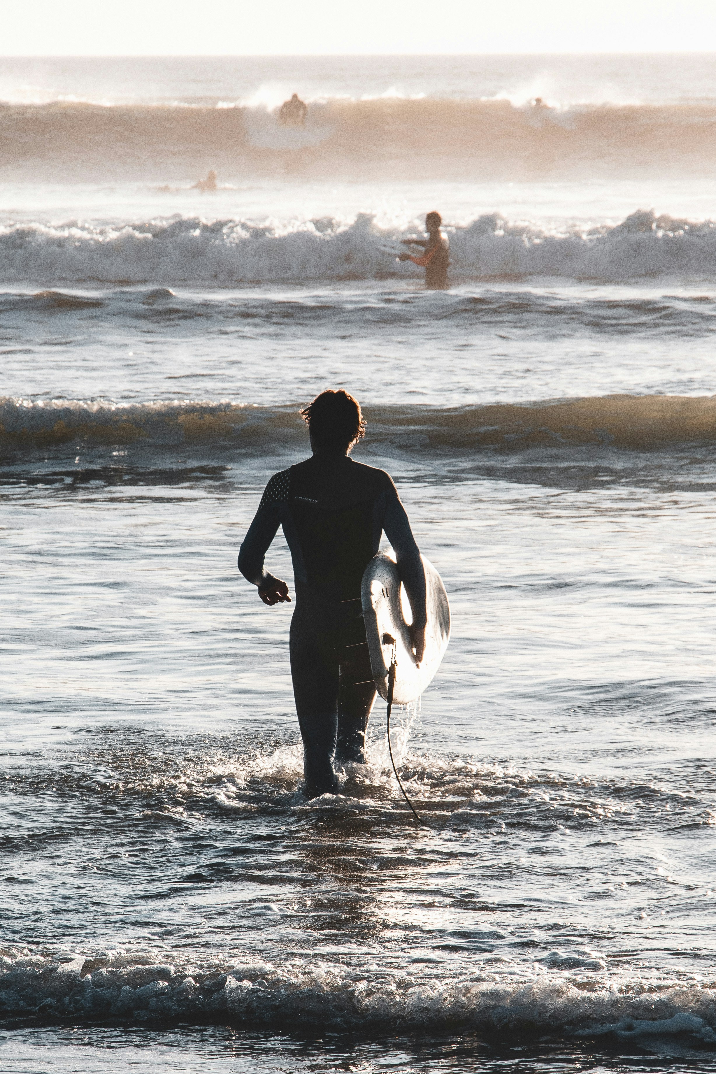 Un uomo in piedi nell'oceano che tiene una tavola da surf