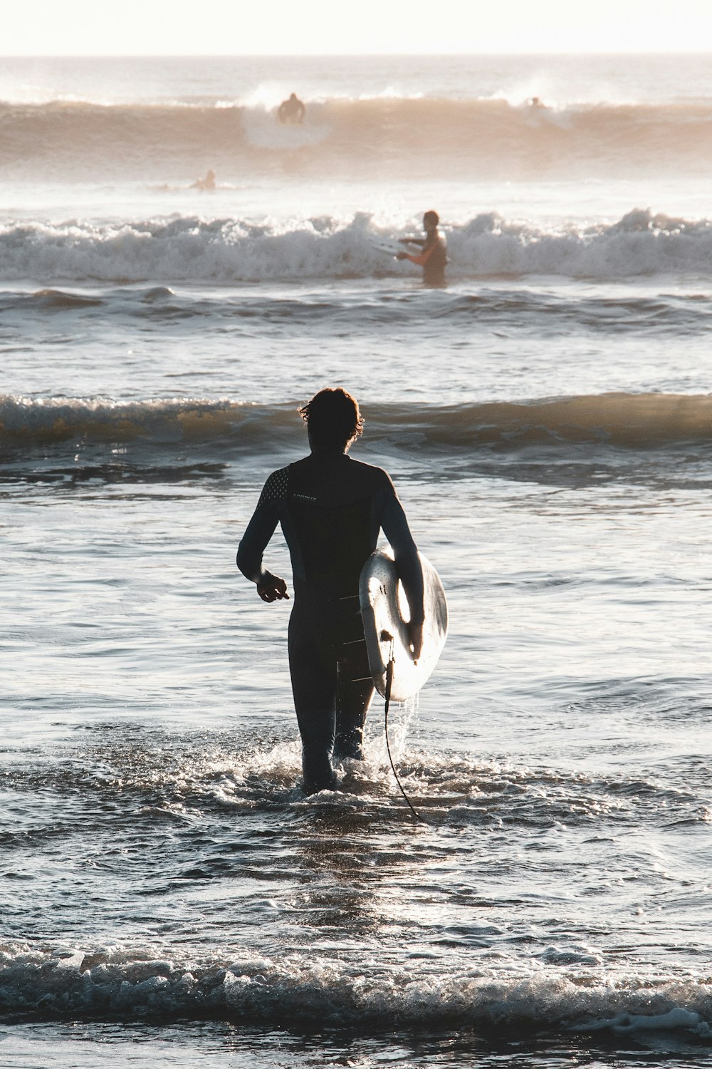 a man standing in the ocean holding a surfboard