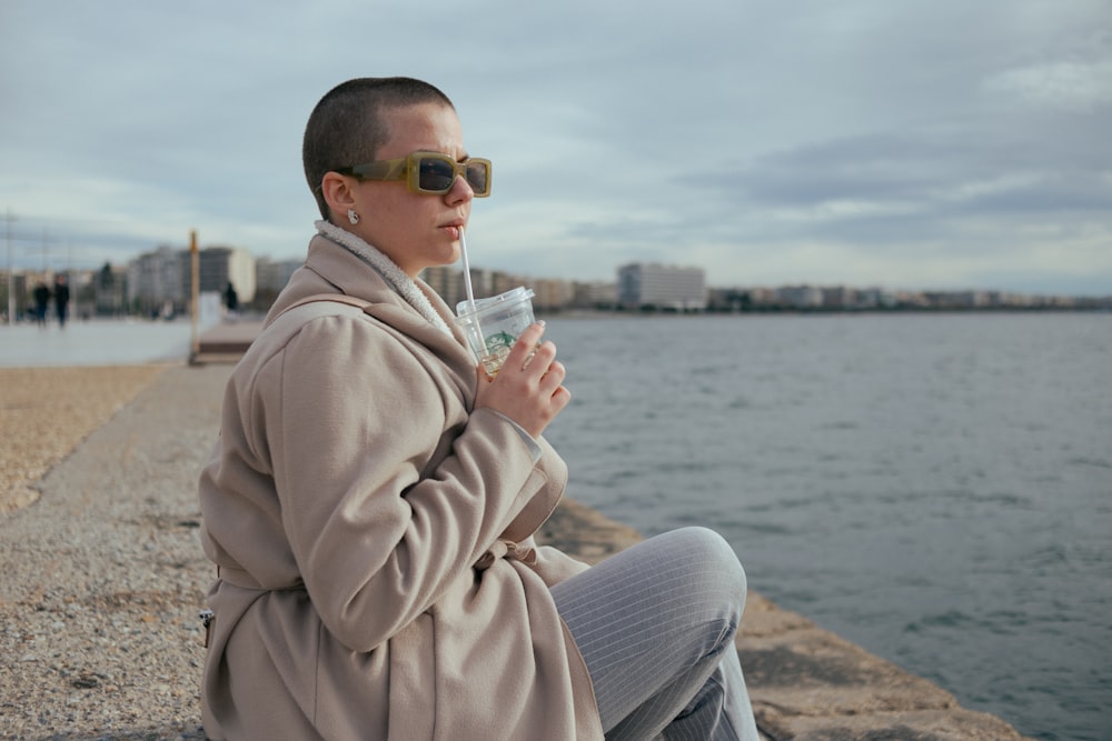 a woman sitting on a wall next to a body of water