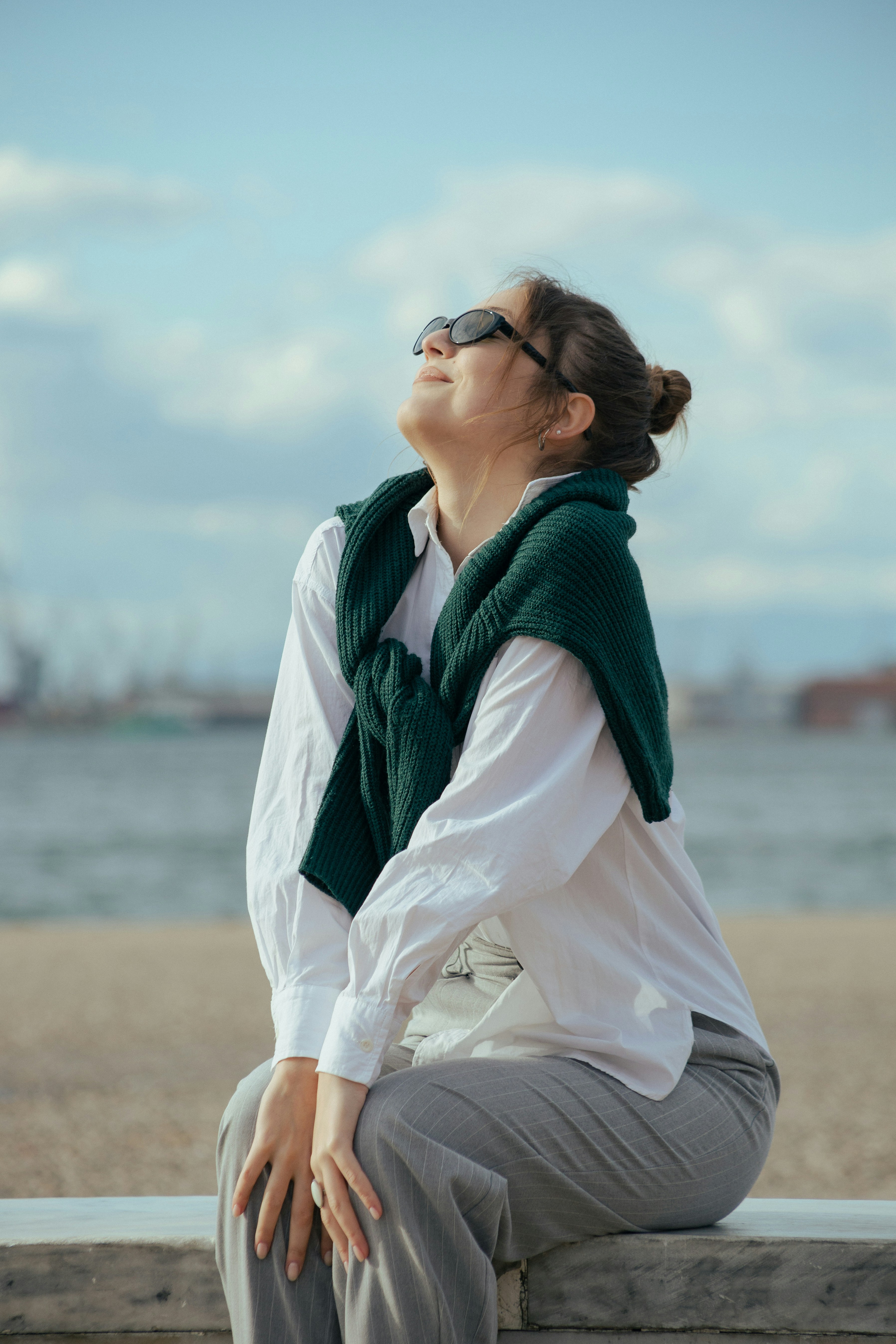 a woman sitting on a bench looking up at the sky