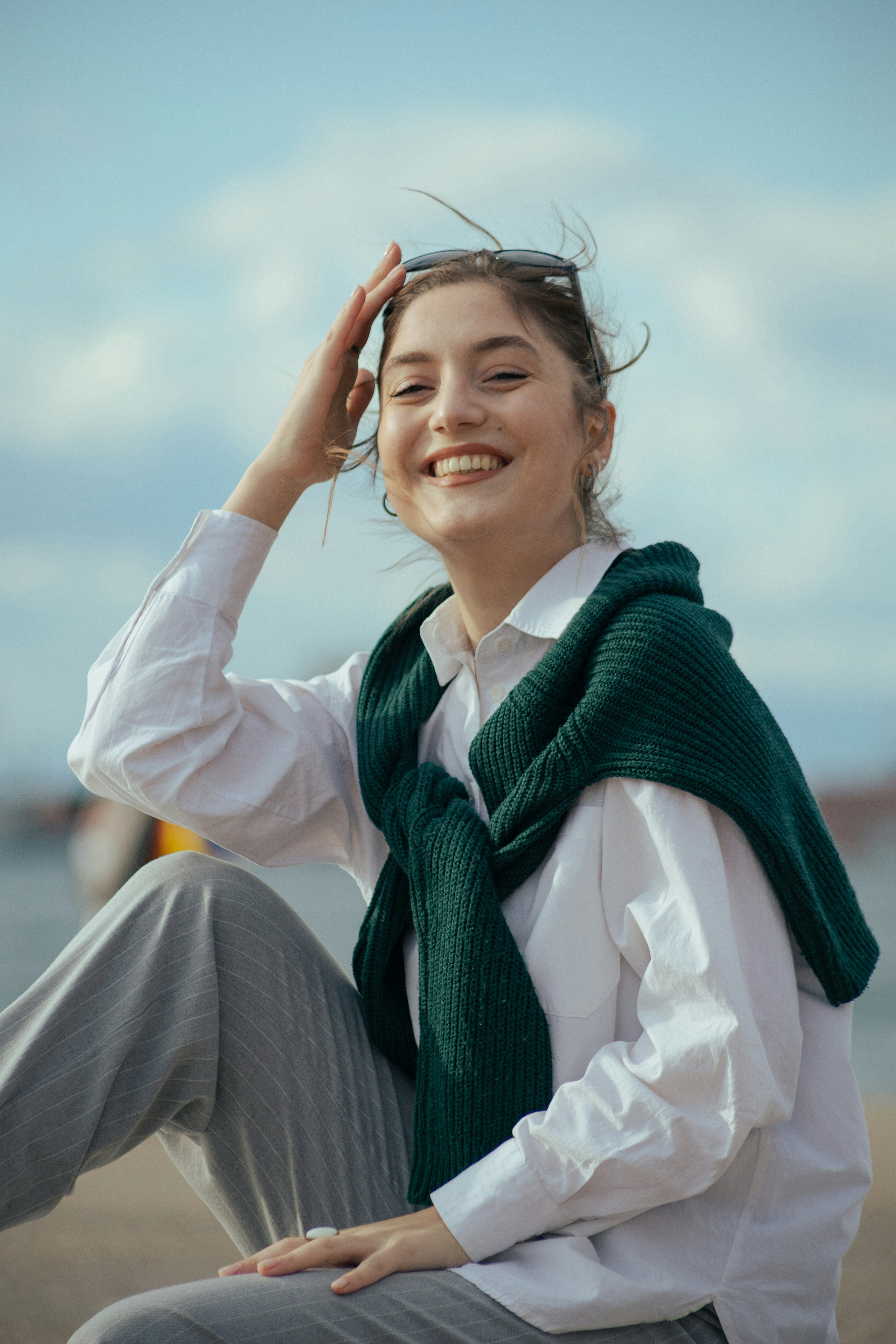 a woman sitting on the beach wearing a green scarf
