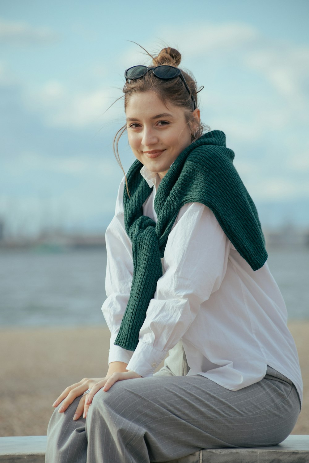 a woman sitting on a bench with a scarf around her neck