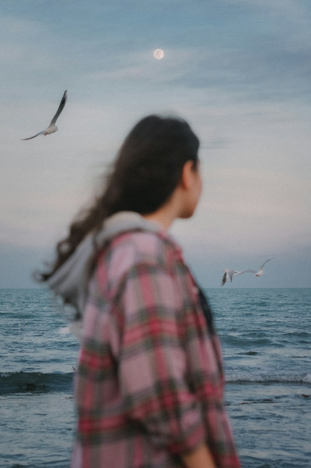 a woman standing on top of a beach next to the ocean