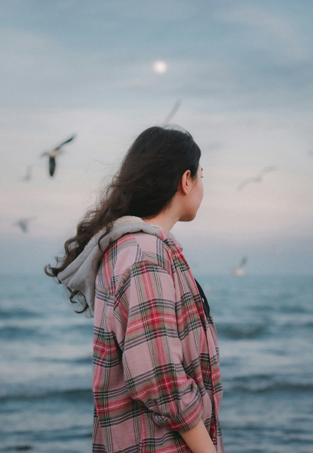 a woman standing on a beach looking at the ocean