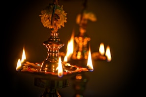 Close-up of a traditional Indian oil lamp glowing softly against a sandstone backdrop.