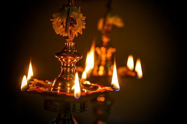 Close-up of handcrafted brass temple lamps glowing softly in a serene Kerala temple setting.