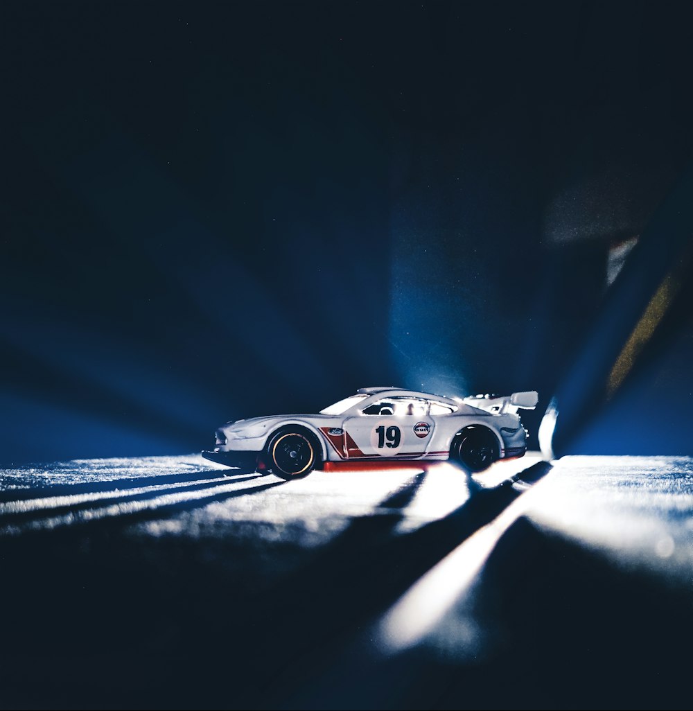 a white race car driving on a road at night