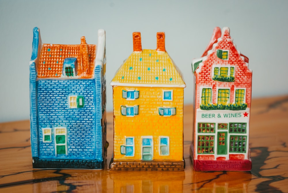three small ceramic houses sitting on top of a wooden table