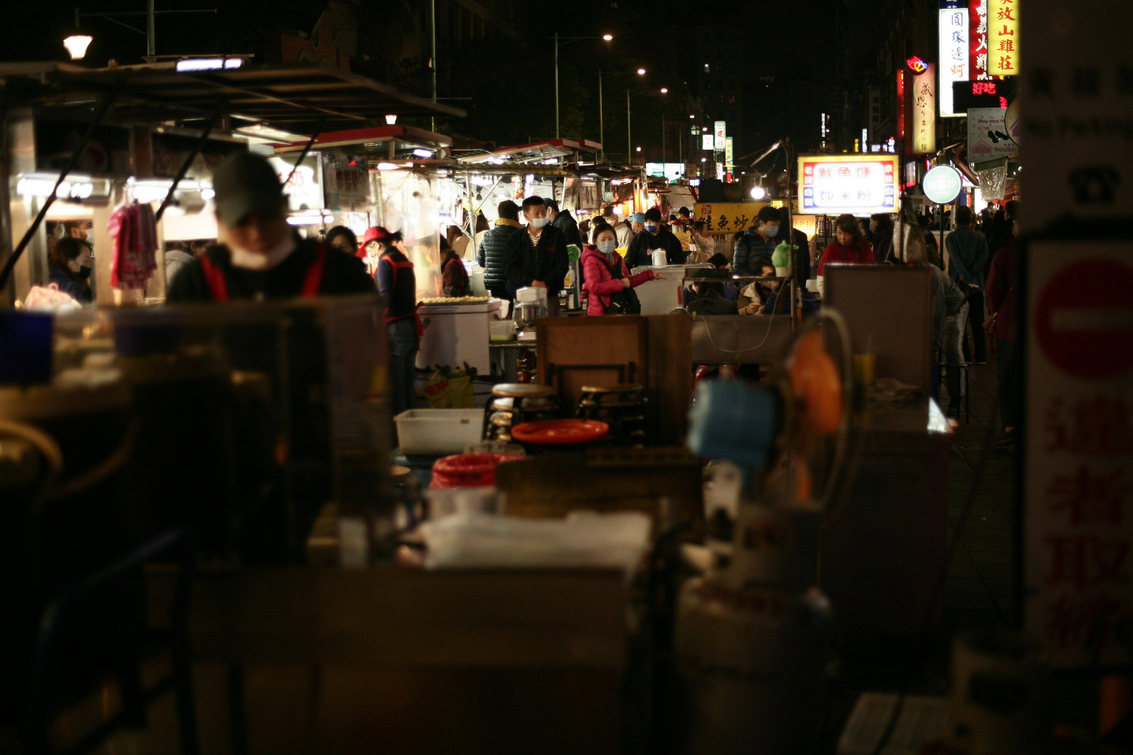 a group of people walking around a market at night