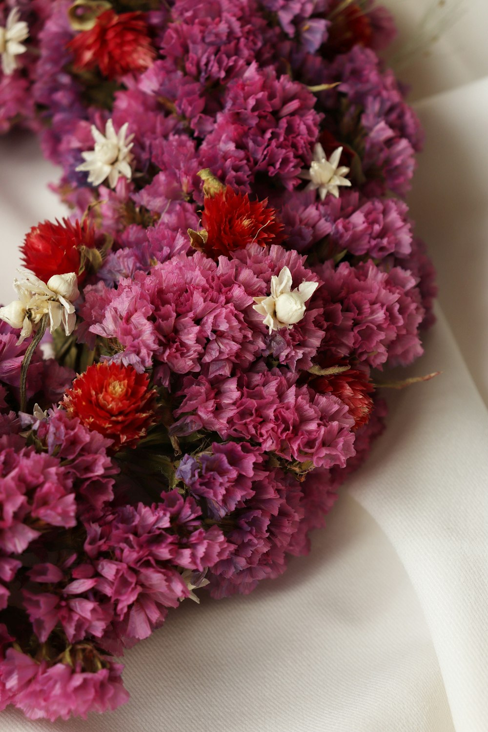 a bunch of purple and red flowers on a white cloth