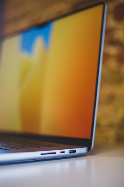 Close-up of hands working on a sleek laptop with branding designs on screen