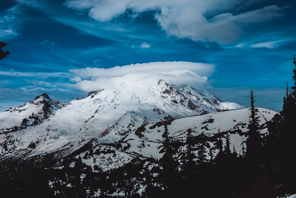 a snow covered mountain under a cloudy blue sky