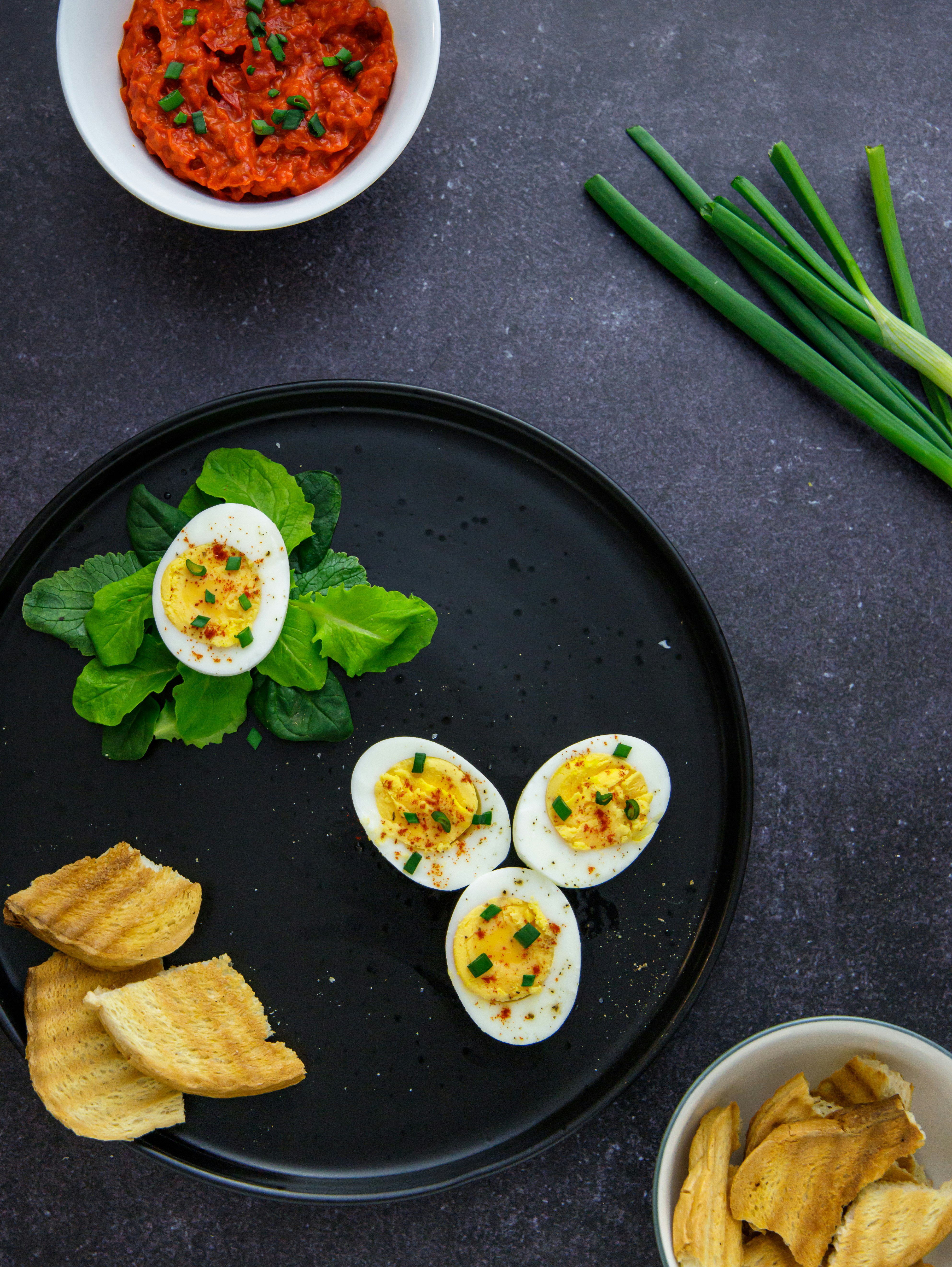 a black plate topped with hard boiled eggs and chips