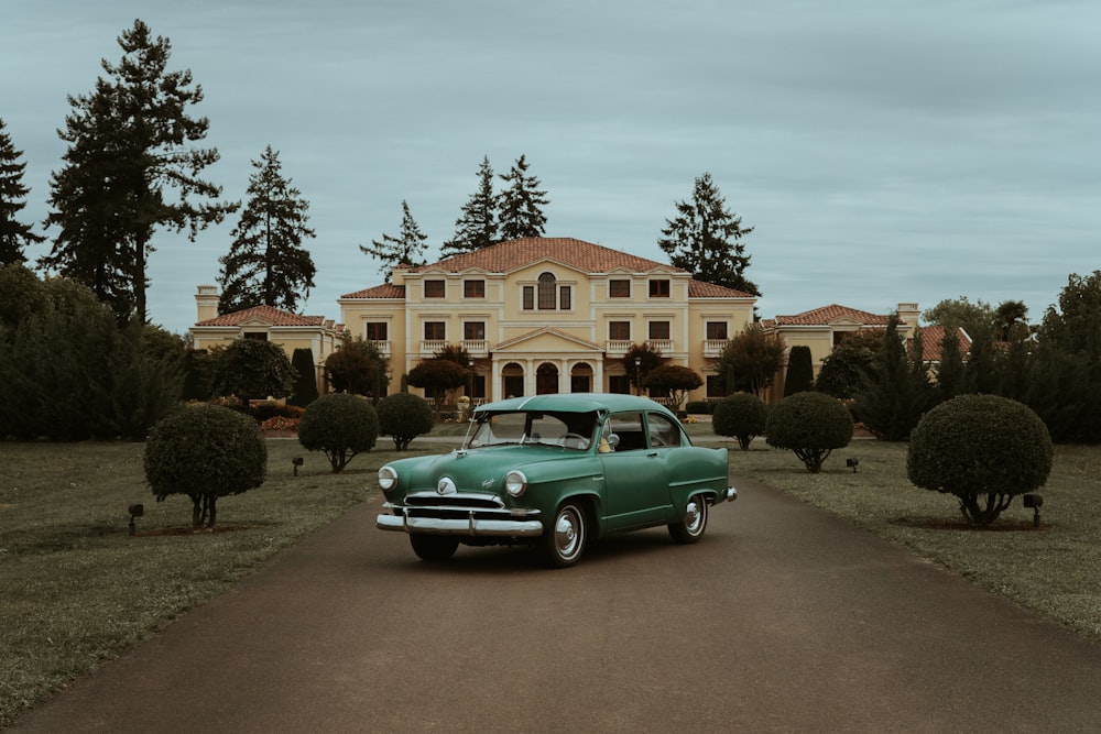 a green car parked in front of a large house