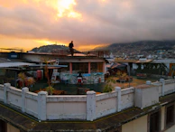 A serene urban rooftop scene at sunset, with someone wearing a nubevibe shirt gazing at the clouds.
