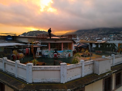 rmthepoet performing passionately on an urban rooftop at sunset, city skyline behind him