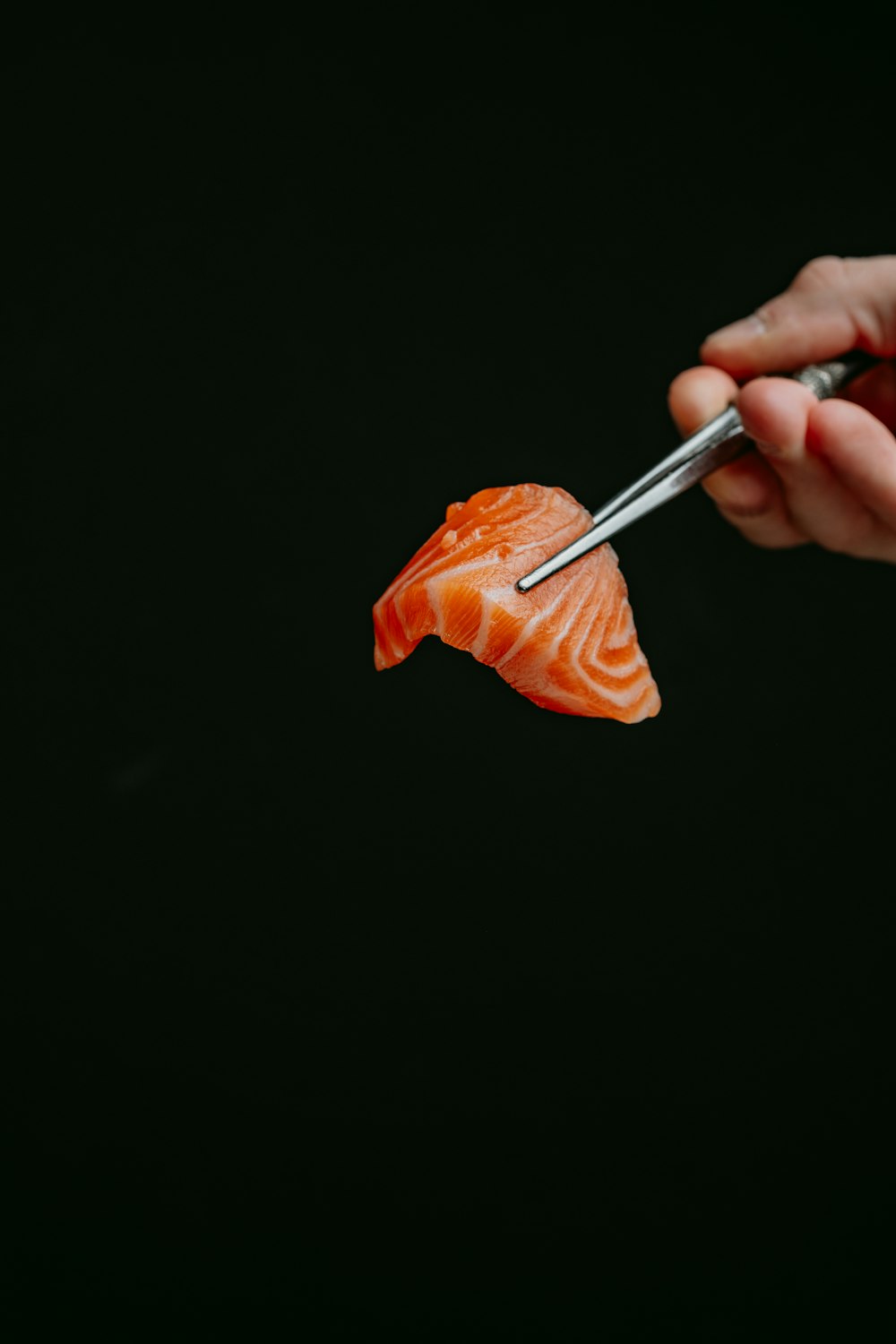 una persona che taglia un pezzo di salmone con un paio di pinze