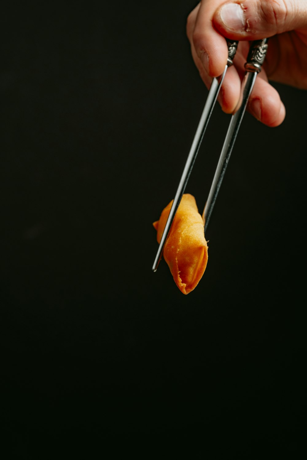 a person holding a pair of chopsticks over a piece of food