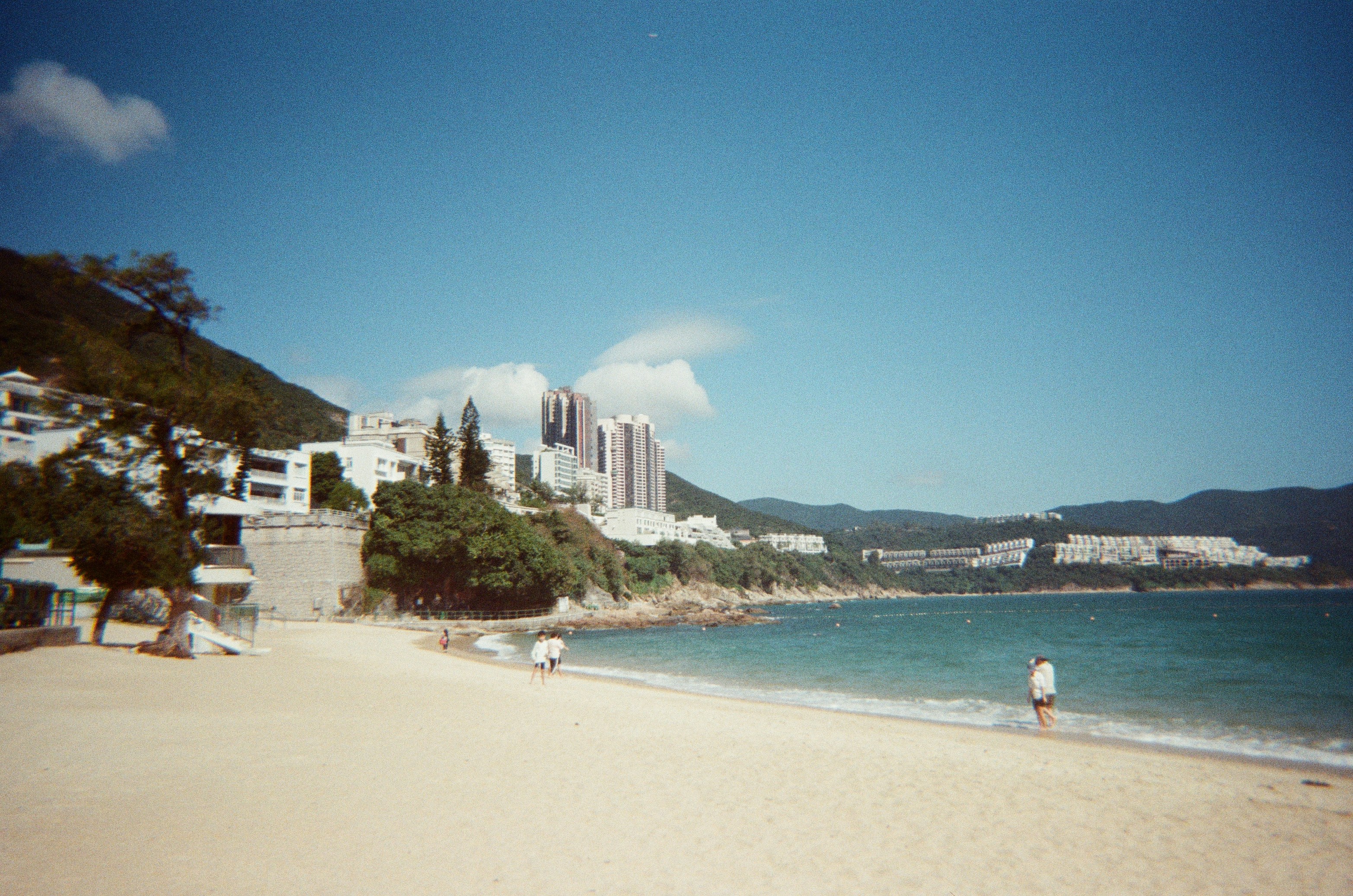 a beach with people walking on it and buildings in the background