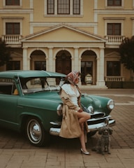a woman sitting on the hood of a green car