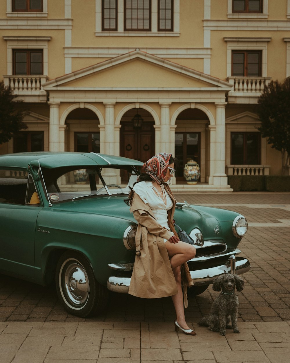 a woman sitting on the hood of a green car