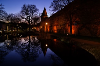 The serene waterside view of an Irish castle ruin at sunset, with soft golden light reflecting on the water.