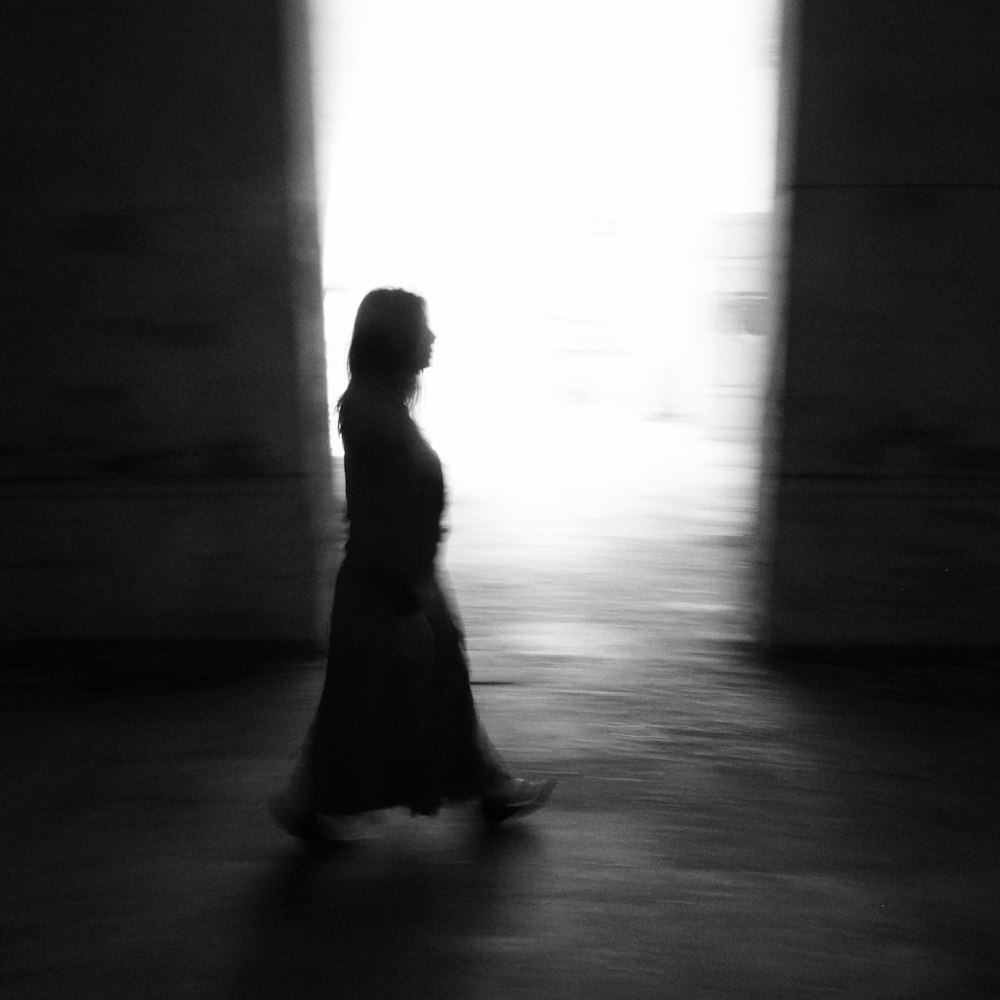 a black and white photo of a woman walking