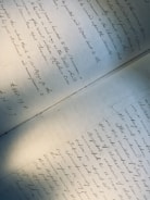 A handwritten document featuring elegant cursive writing, covering two pages laid out on a flat surface. The text is slightly tilted, with shadows cast across the paper, giving a sense of age and historical importance.