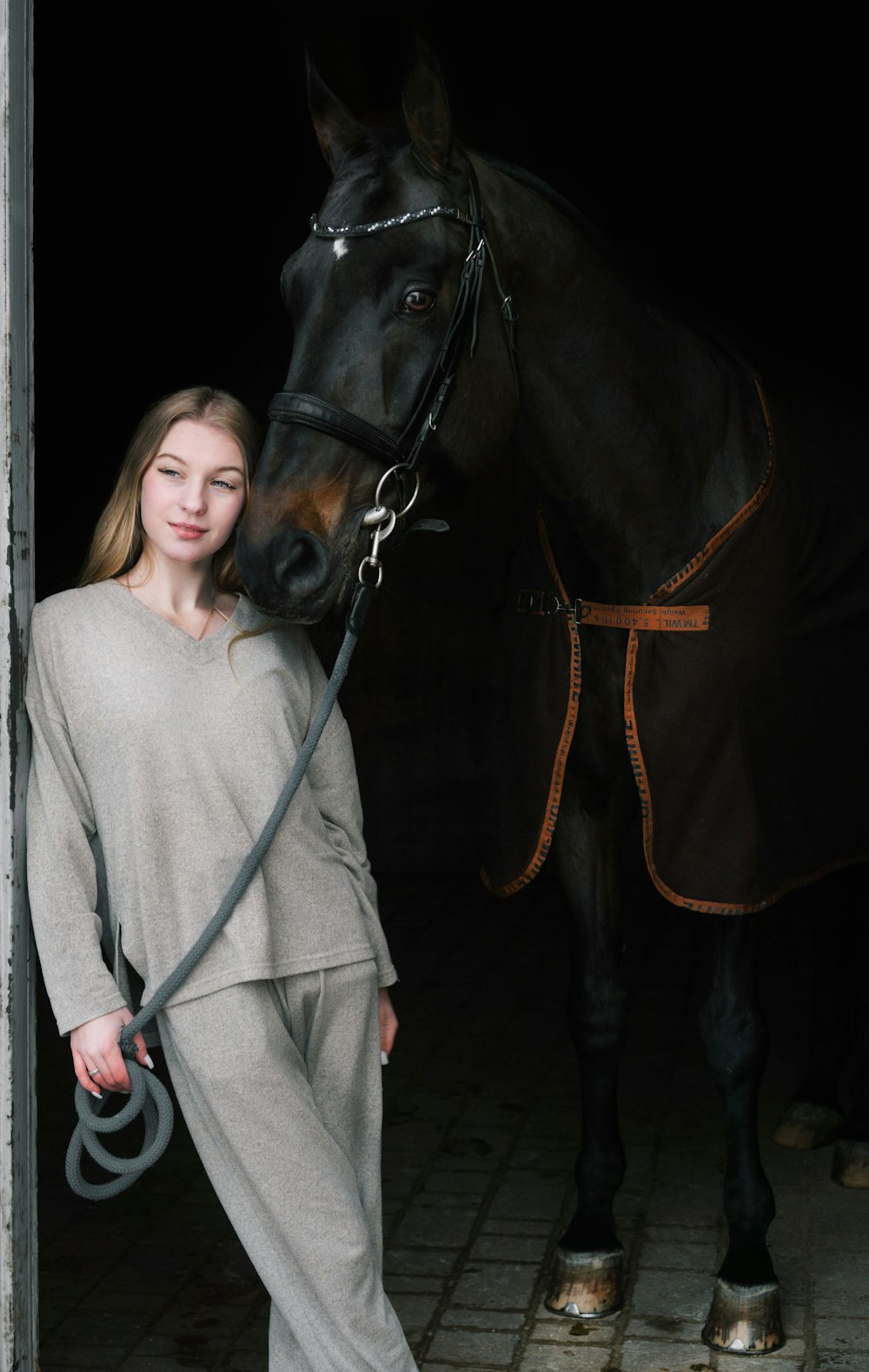 a woman standing next to a horse in a stable