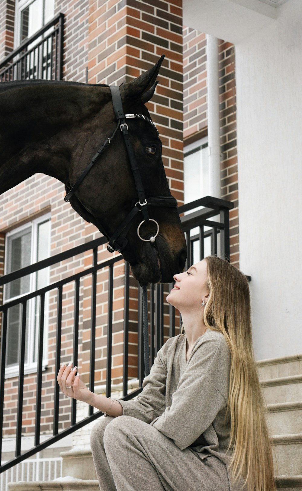 a woman sitting on the steps with a horse on her head