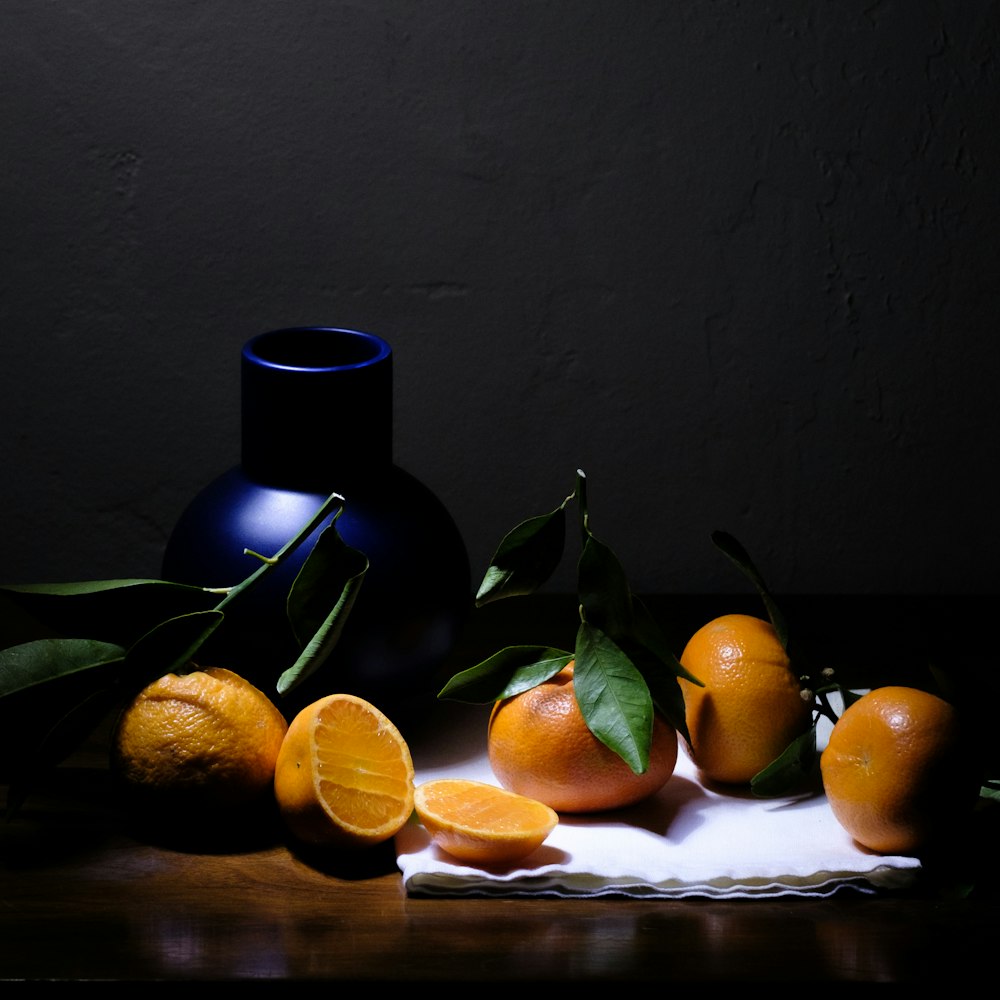 a still life of oranges and a vase on a table
