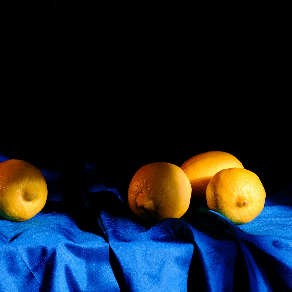 three oranges are sitting on a blue cloth