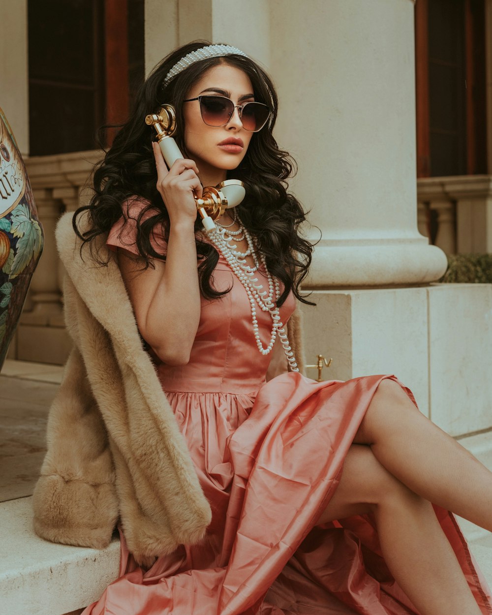 a woman in a pink dress is talking on a cell phone