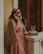 a woman in a pink dress talking on a phone