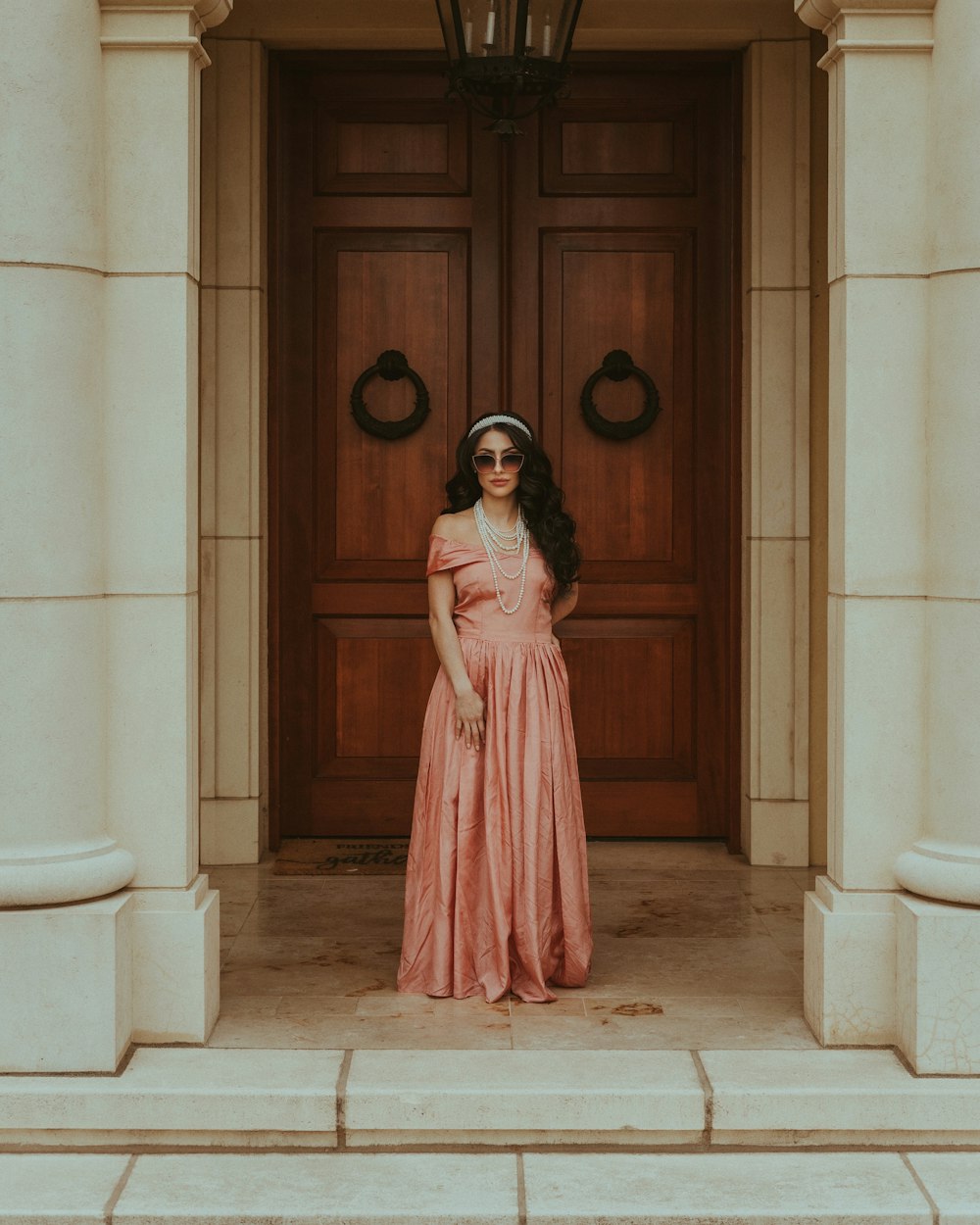 uma mulher em um vestido rosa em frente a uma porta