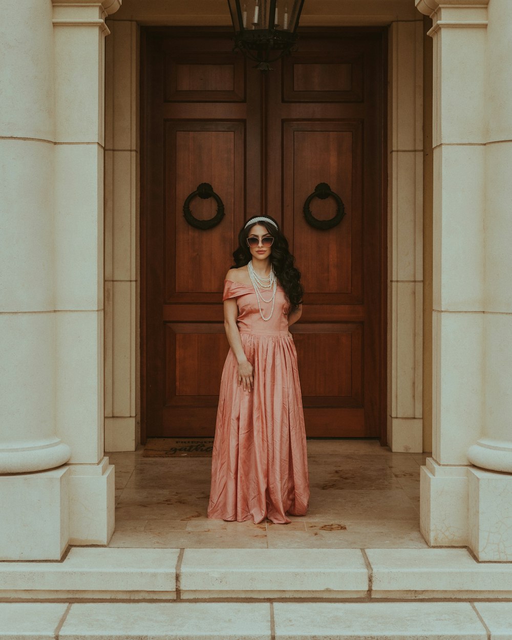 a woman in a pink dress standing in front of a door