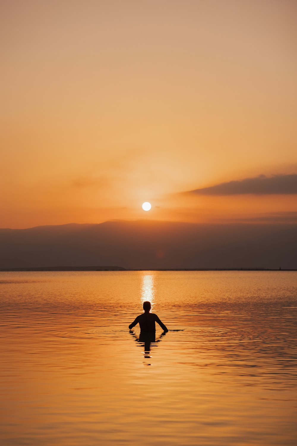 eine Person in einem Gewässer bei Sonnenuntergang