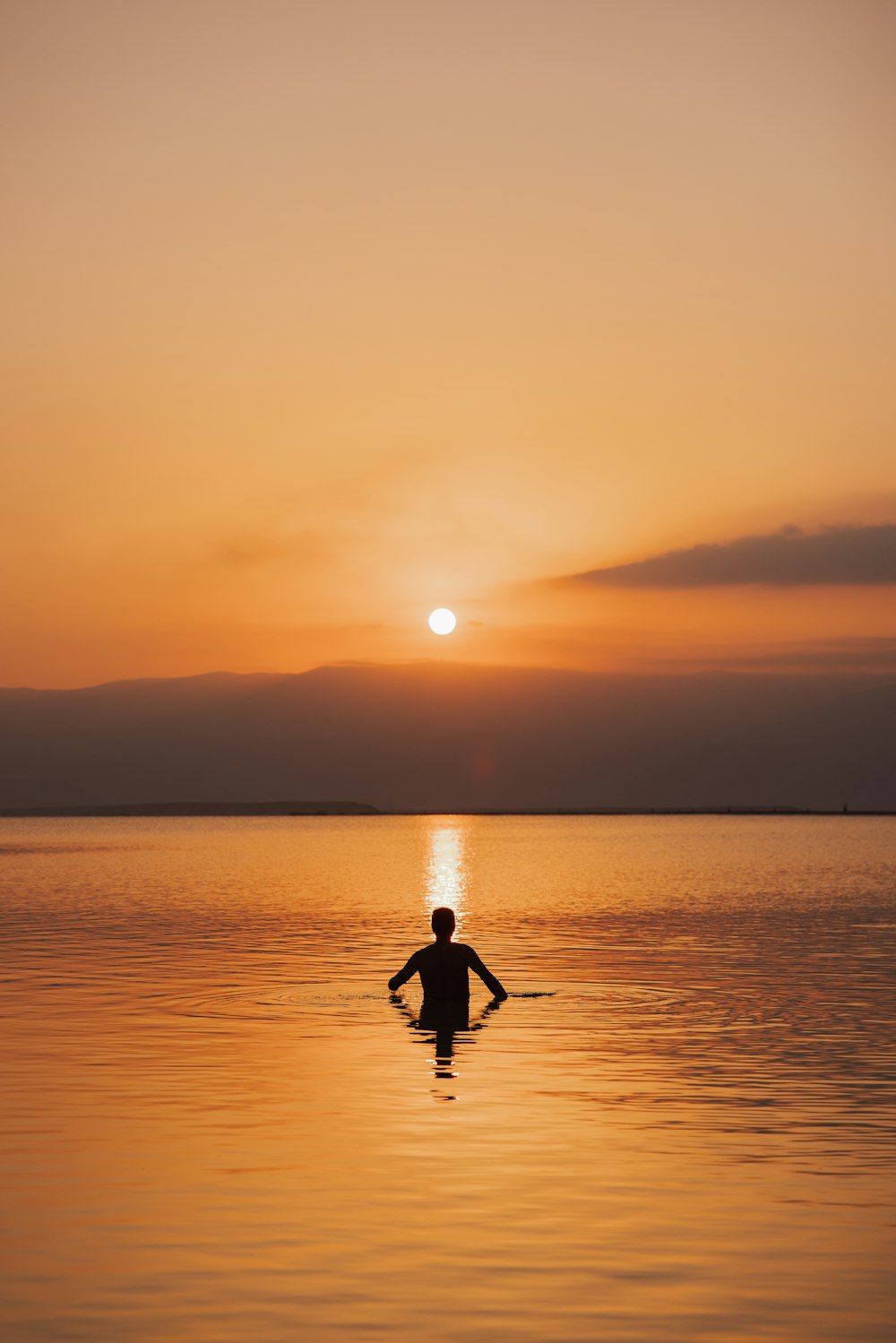 a person in a body of water at sunset