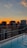 Sunset view from a luxury penthouse balcony overlooking the city skyline.