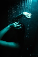 a woman's hand reaching for a shower head