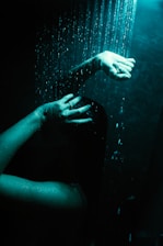 a woman's hand reaching for a shower head
