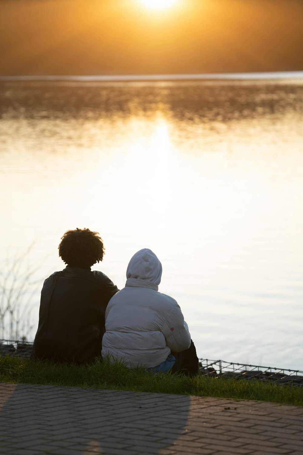 a couple of people sitting next to a body of water